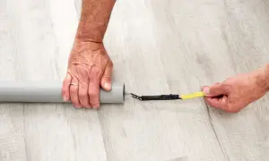Ręce przygotowują kabel do przeciągnięcia przez peszel, owijając jego koniec taśmą izolacyjną.