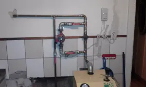 Montaż pompy CO w układzie otwartym. Widoczna instalacja miedziana, czerwona pompa, zawory i fragment kotła.