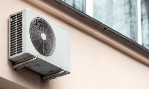 Jednostka zewnętrzna klimatyzatora zamontowana na ścianie bloku, gotowa do montażu na dachu.