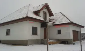 Zimowy dom z ośnieżonym dachem. Na ścianie wschodniej, pod okapem, znajduje się czujnik pogodowy do pieca gazowego, gdzie zamontować go podpowiada strzałka.