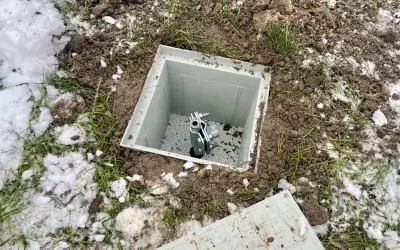 Uziom szpilkowy w piwnicy, gotowy do podłączenia. Widać metalową szpilę w plastikowej obudowie, otoczoną ziemią i resztkami śniegu.
