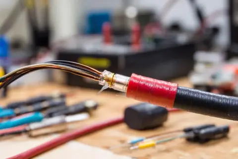 Przewody elektryczne z widoczną izolacją, zabezpieczone taśmą.
