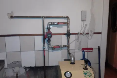 Montaż pompy CO w układzie otwartym. Widoczna instalacja miedziana, czerwona pompa, zawory i fragment kotła.