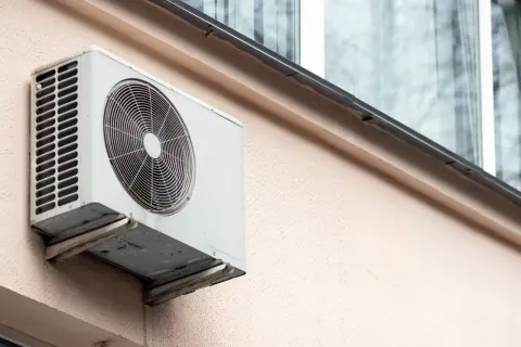 Jednostka zewnętrzna klimatyzatora zamontowana na ścianie bloku, gotowa do montażu na dachu.