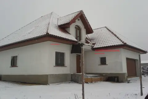 Zimowy dom z ośnieżonym dachem. Na ścianie wschodniej, pod okapem, znajduje się czujnik pogodowy do pieca gazowego, gdzie zamontować go podpowiada strzałka.