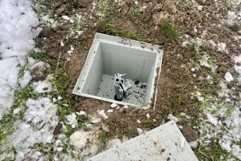 Uziom szpilkowy w piwnicy, gotowy do podłączenia. Widać metalową szpilę w plastikowej obudowie, otoczoną ziemią i resztkami śniegu.