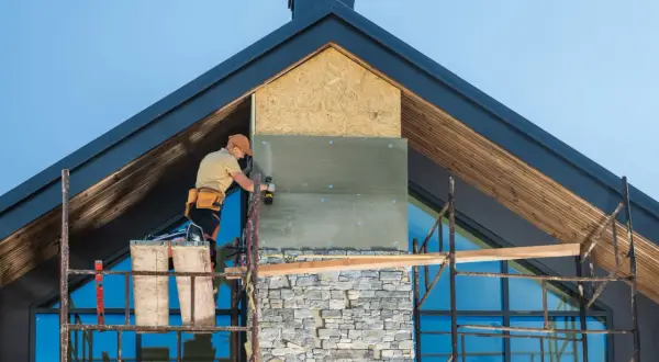 Pracownik montuje izolację na kominie, który będzie wykończony kamieniem. Różne rodzaje kominów wymagają różnych metod instalacji.