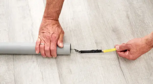 Ręce przygotowują kabel do przeciągnięcia przez peszel, owijając jego koniec taśmą izolacyjną.