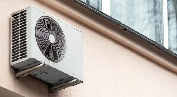 Jednostka zewnętrzna klimatyzatora zamontowana na ścianie bloku, gotowa do montażu na dachu.