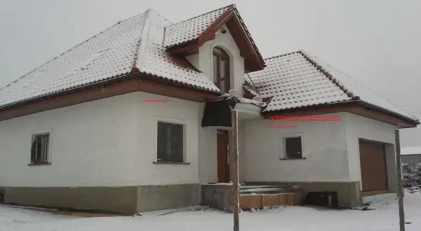 Zimowy dom z ośnieżonym dachem. Na ścianie wschodniej, pod okapem, znajduje się czujnik pogodowy do pieca gazowego, gdzie zamontować go podpowiada strzałka.