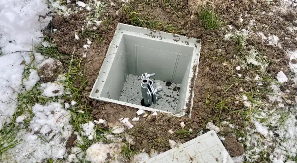 Uziom szpilkowy w piwnicy, gotowy do podłączenia. Widać metalową szpilę w plastikowej obudowie, otoczoną ziemią i resztkami śniegu.