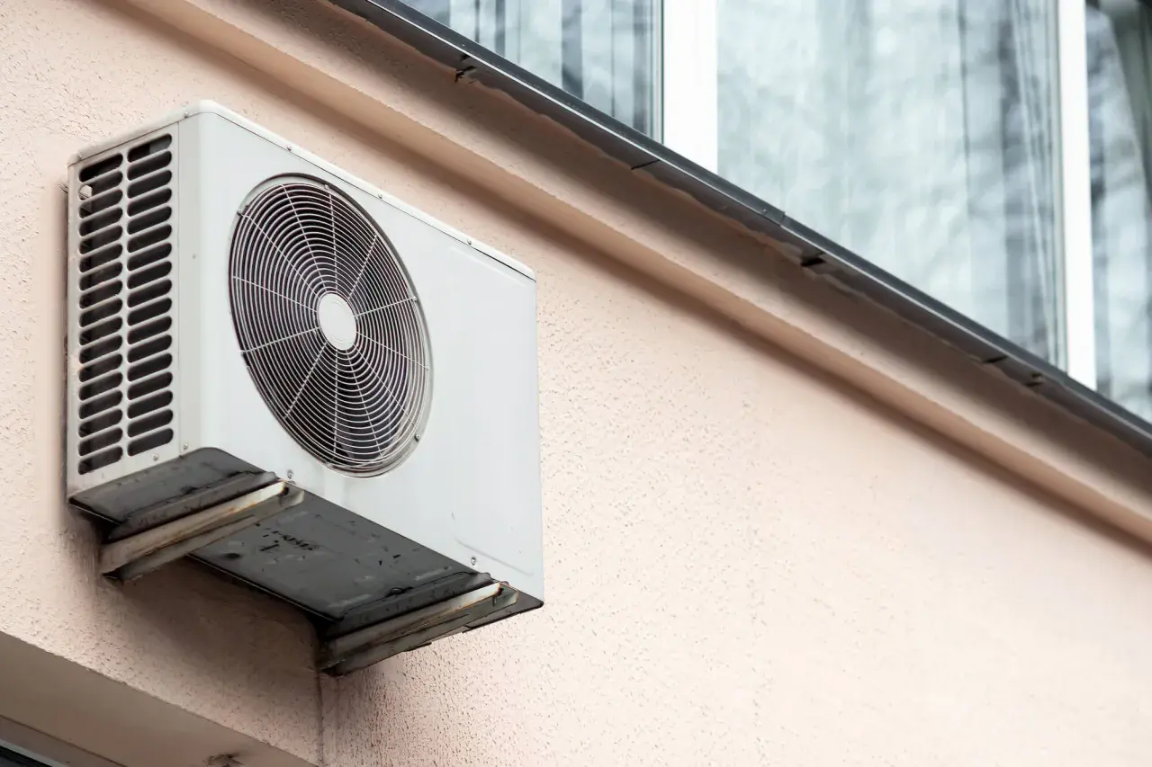 Jednostka zewnętrzna klimatyzatora zamontowana na ścianie bloku, gotowa do montażu na dachu.