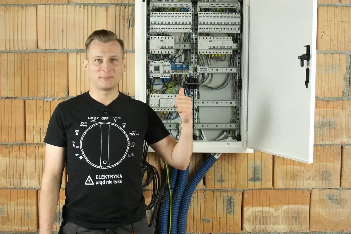 Elektryk pokazuje rozdzielnicę elektryczną, wyjaśniając, co to jest RCBO. Kciuk w g&oacute;rę.