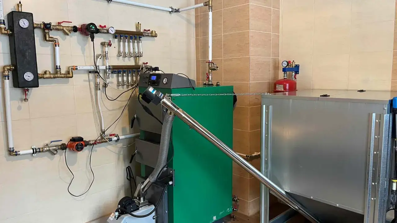 Kotłownia z zielonym kotłem na pellet. Widoczny panel sterowania, pompa obiegowa i instalacja hydrauliczna. Nieudane rozpalanie kod 17.