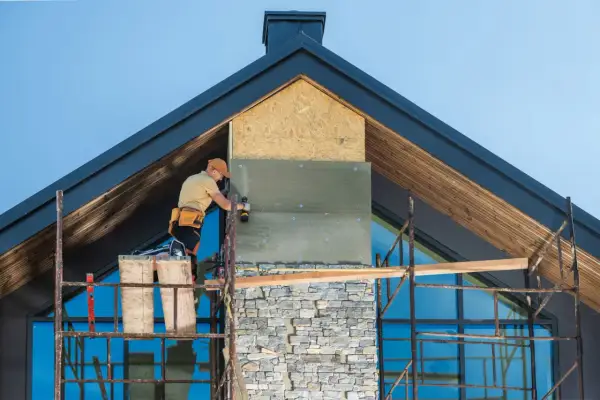 Pracownik montuje izolację na kominie, który będzie wykończony kamieniem. Różne rodzaje kominów wymagają różnych metod instalacji.