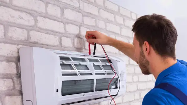 Technik sprawdza klimatyzację, która wydaje dziwny zapach z klimatyzacji w domu.