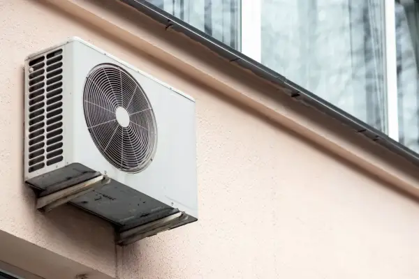 Jednostka zewnętrzna klimatyzatora zamontowana na ścianie bloku, gotowa do montażu na dachu.