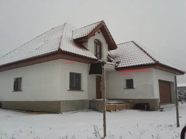 Zimowy dom z ośnieżonym dachem. Na ścianie wschodniej, pod okapem, znajduje się czujnik pogodowy do pieca gazowego, gdzie zamontować go podpowiada strzałka.
