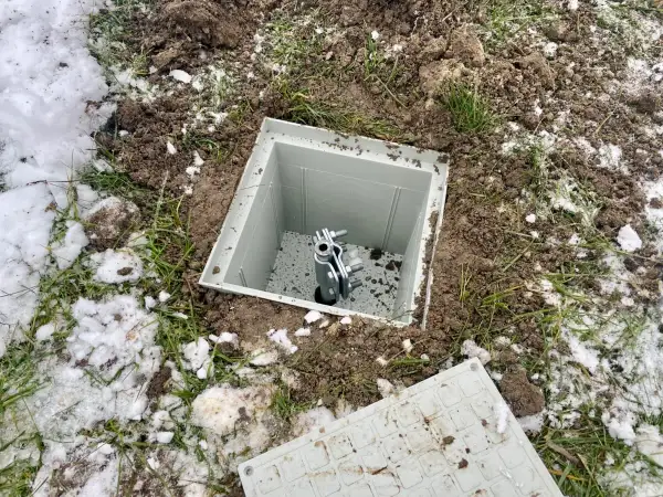 Uziom szpilkowy w piwnicy, gotowy do podłączenia. Widać metalową szpilę w plastikowej obudowie, otoczoną ziemią i resztkami śniegu.